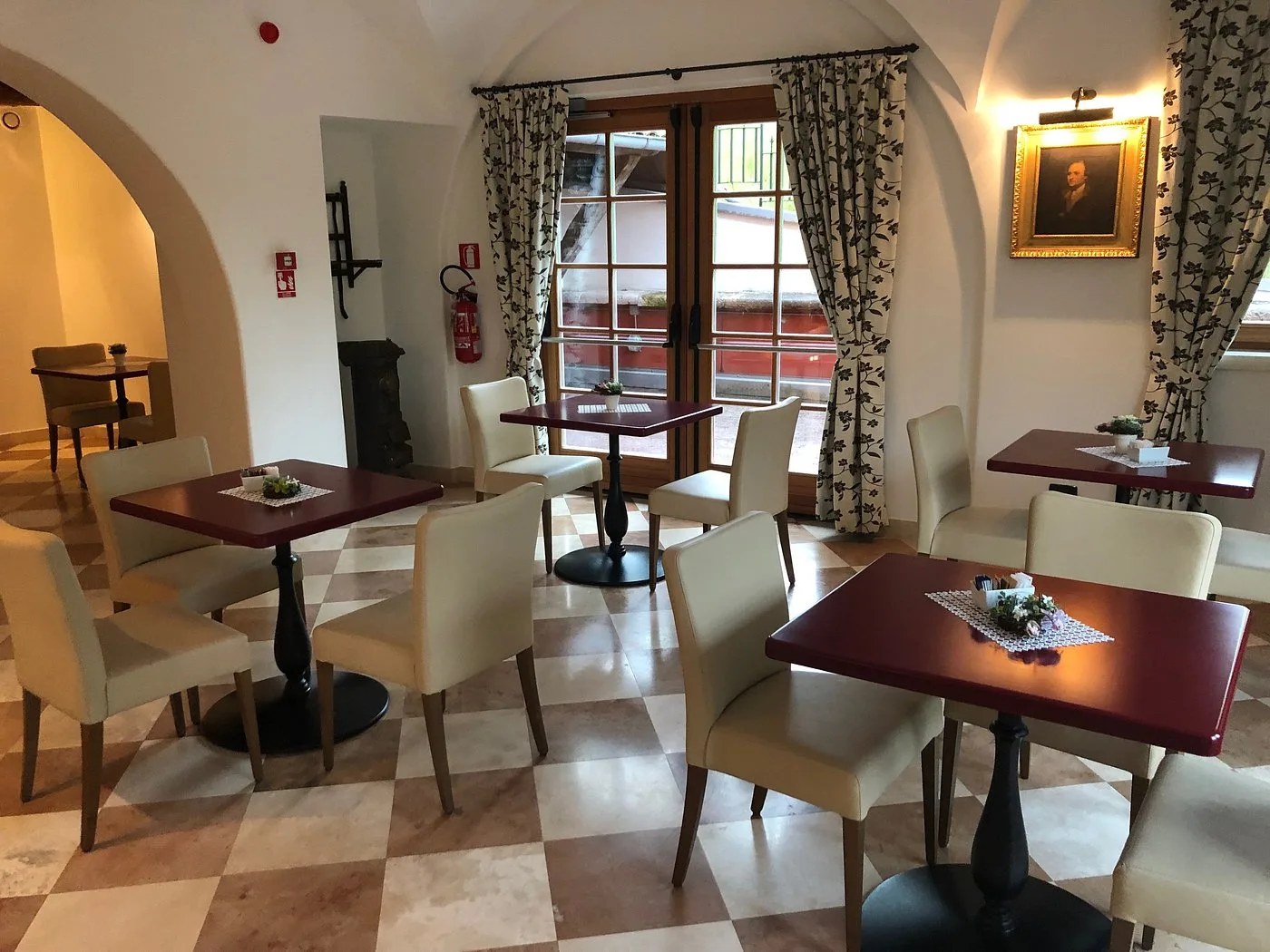 Sala da pranzo con tavoli rossi e pavimento a scacchi