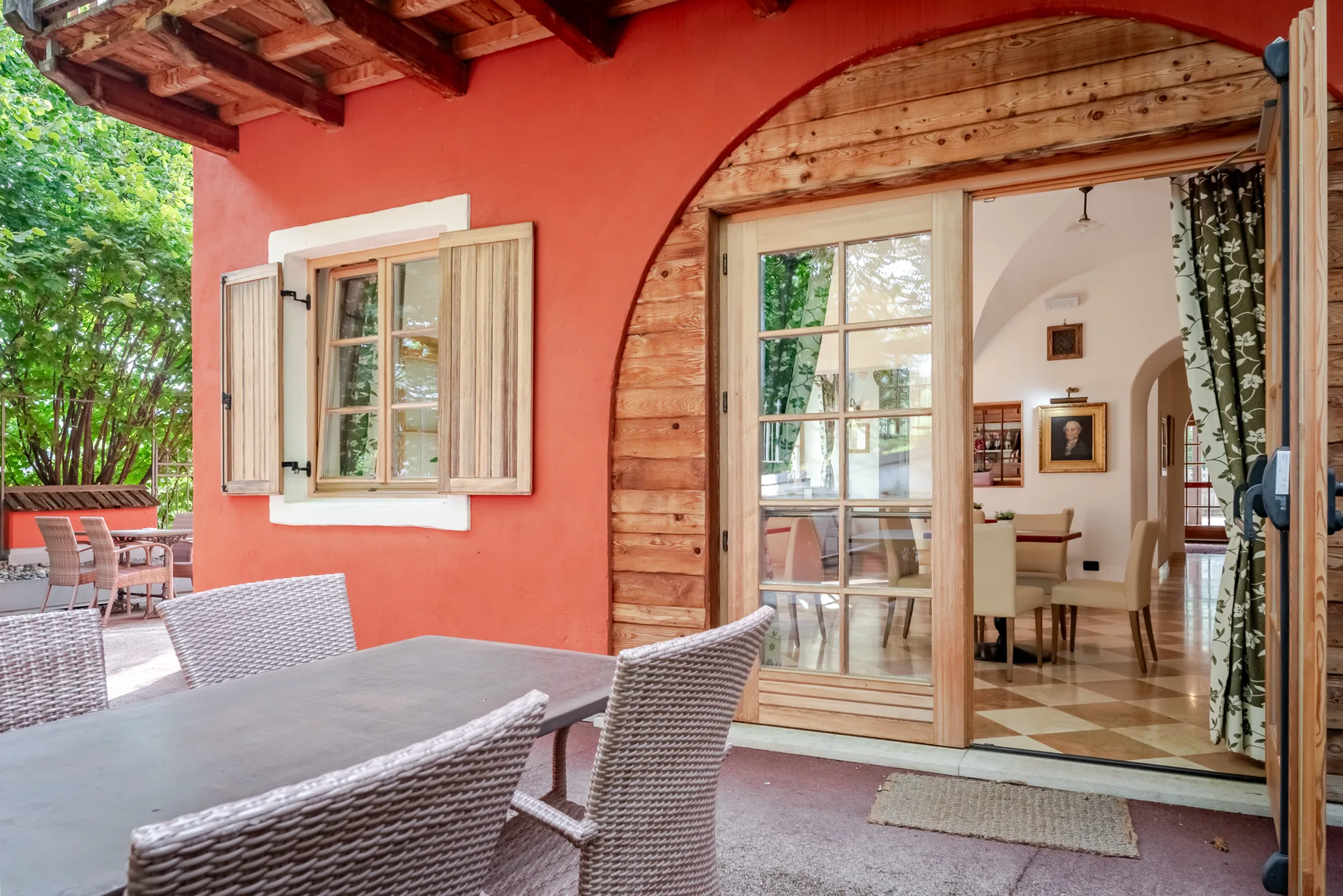 Terrazza esterna con tavolo e sedie in vimini e facciata rossa