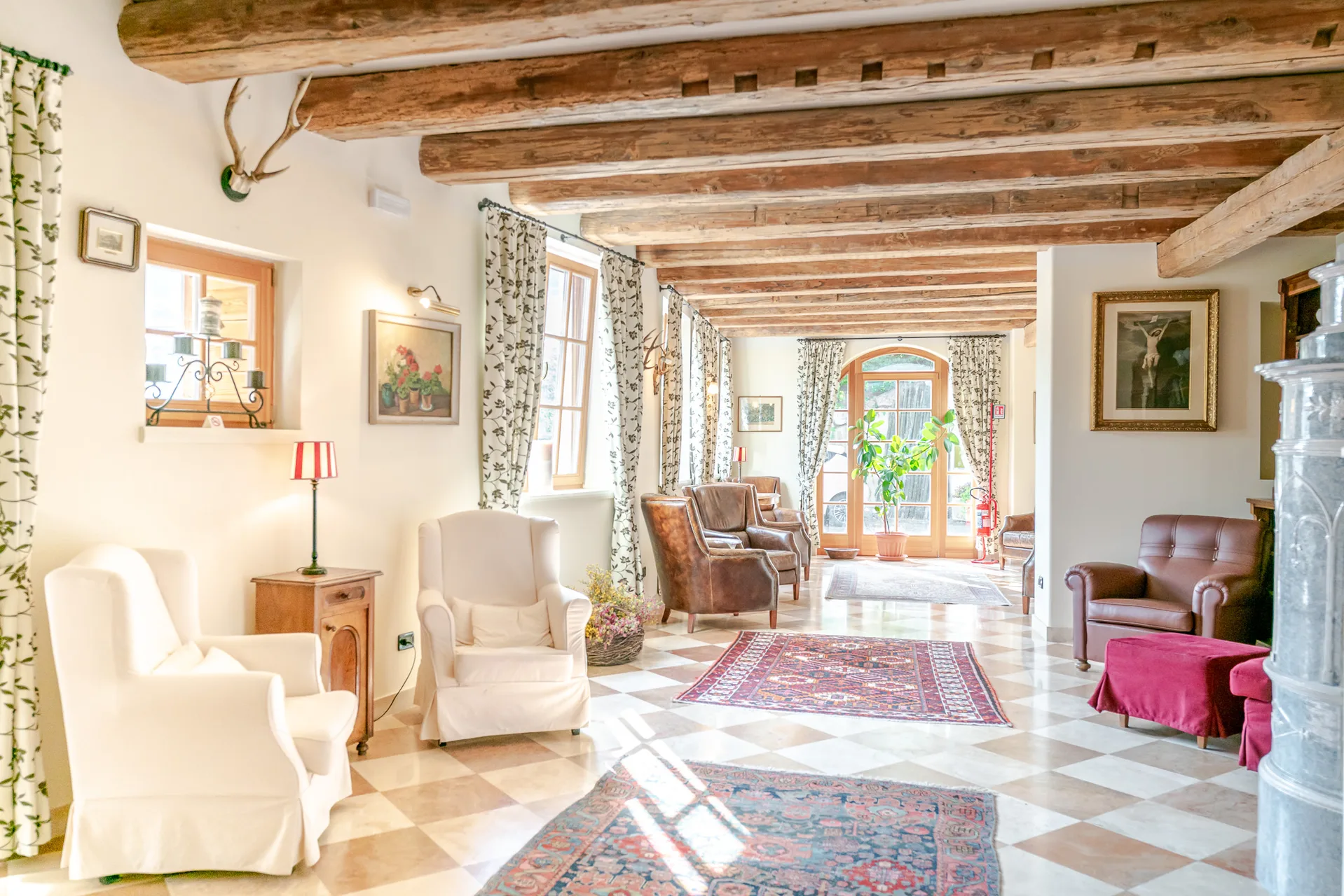 Elegante hall con travi in legno, poltrone bianche e pavimento a scacchi