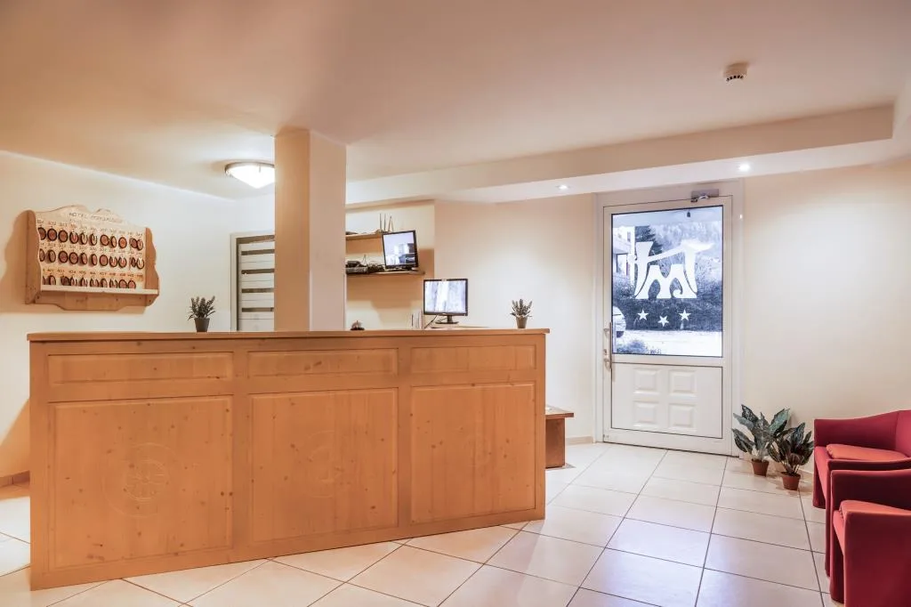 Area reception con bancone in legno, porta d'ingresso e poltrone rosse