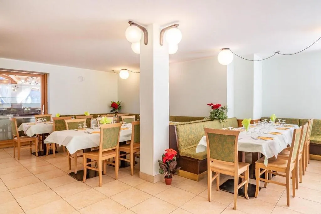 Sala ristorante con tavoli apparecchiati, sedie in legno e panche verdi