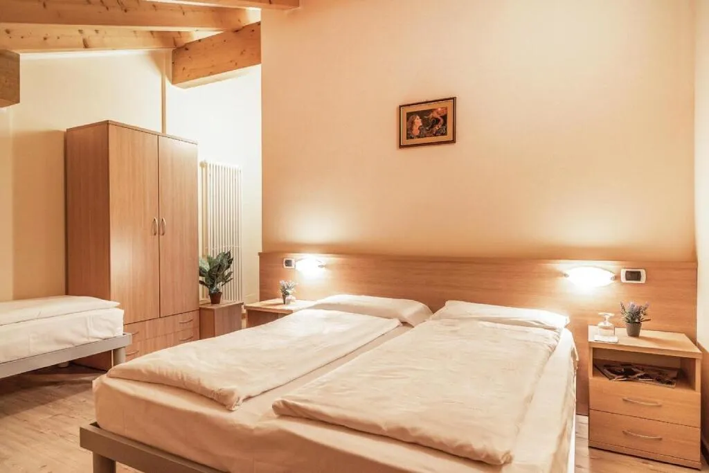 Camera tripla con letti matrimoniale e singolo, armadio e travi in legno
