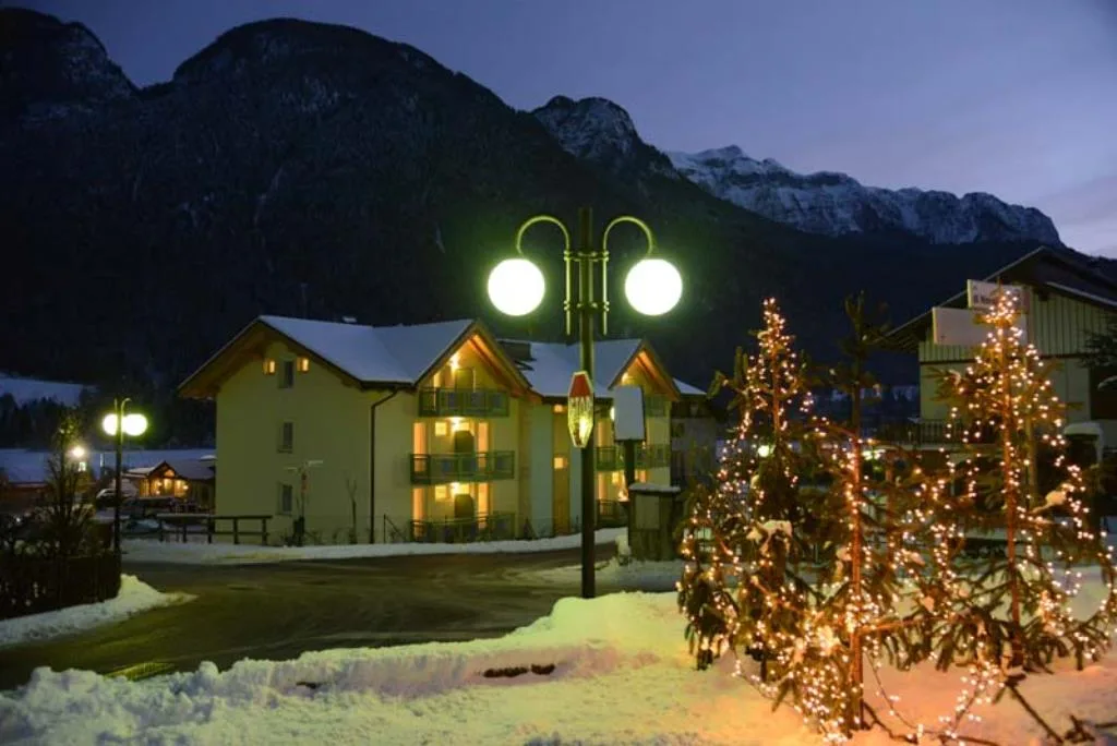 Vista notturna dell'hotel con lampione e alberi di Natale illuminati nella neve