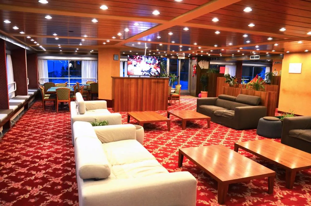 Salotto con divani, tavolini, TV e moquette rossa a motivi floreali