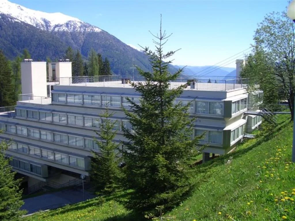 Esterno dell'hotel in estate con prato verde e montagne sullo sfondo