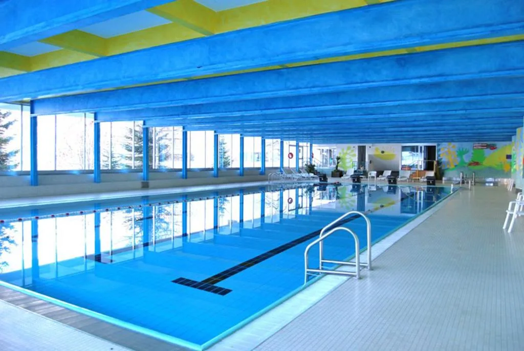 Piscina coperta con soffitto azzurro e giallo e grandi vetrate luminose