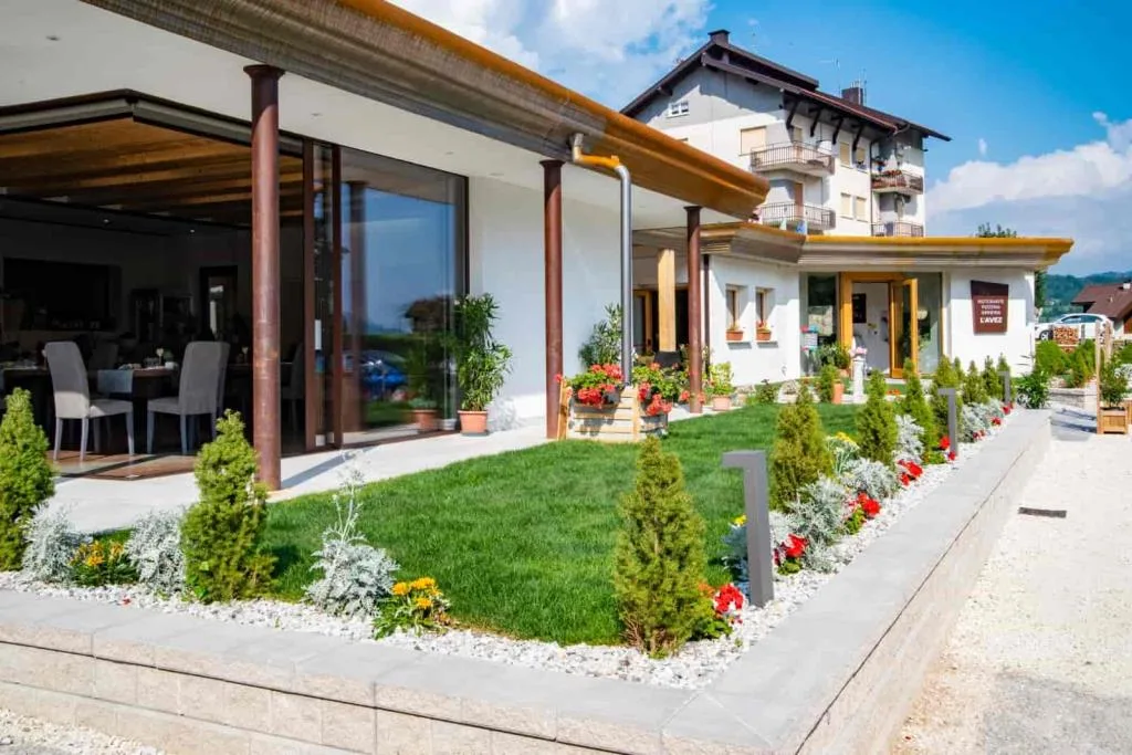 Esterno del ristorante con veranda a vetri, giardino curato e aiuole fiorite