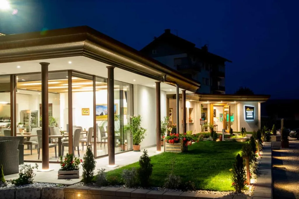 Esterno notturno del ristorante con veranda illuminata e giardino con luci