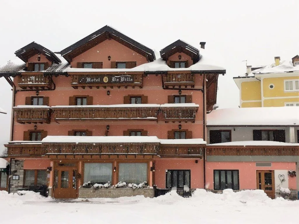 Facciata rosa dell'hotel coperta di neve durante una nevicata