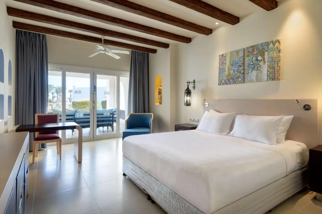Camera matrimoniale elegante con letto king size, travi a vista, scrivania e ampia porta finestra sul terrazzo
